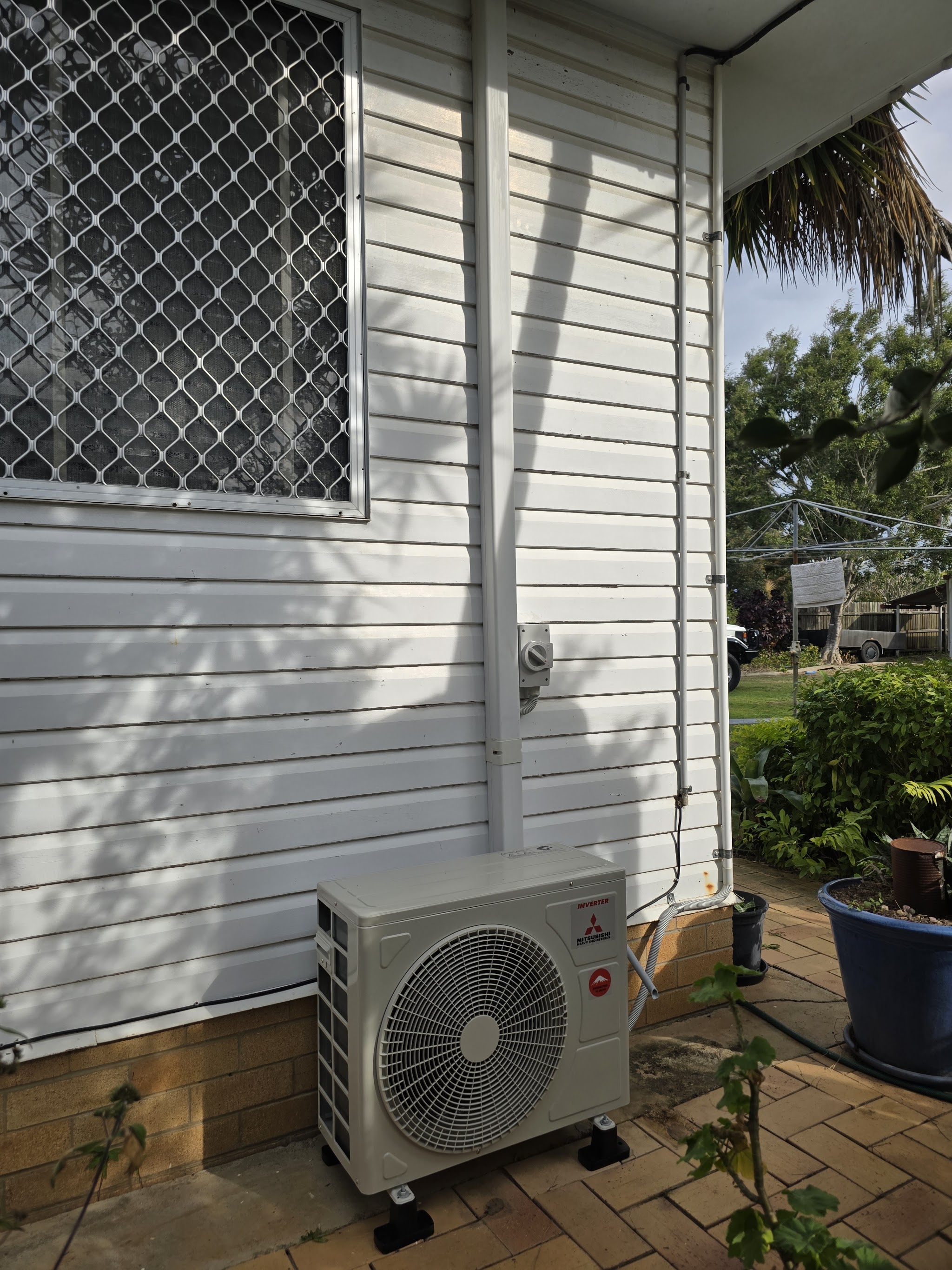 Mitsubishi Heavy Industries outdoor unit mounted on stands beside a white weatherboard wall